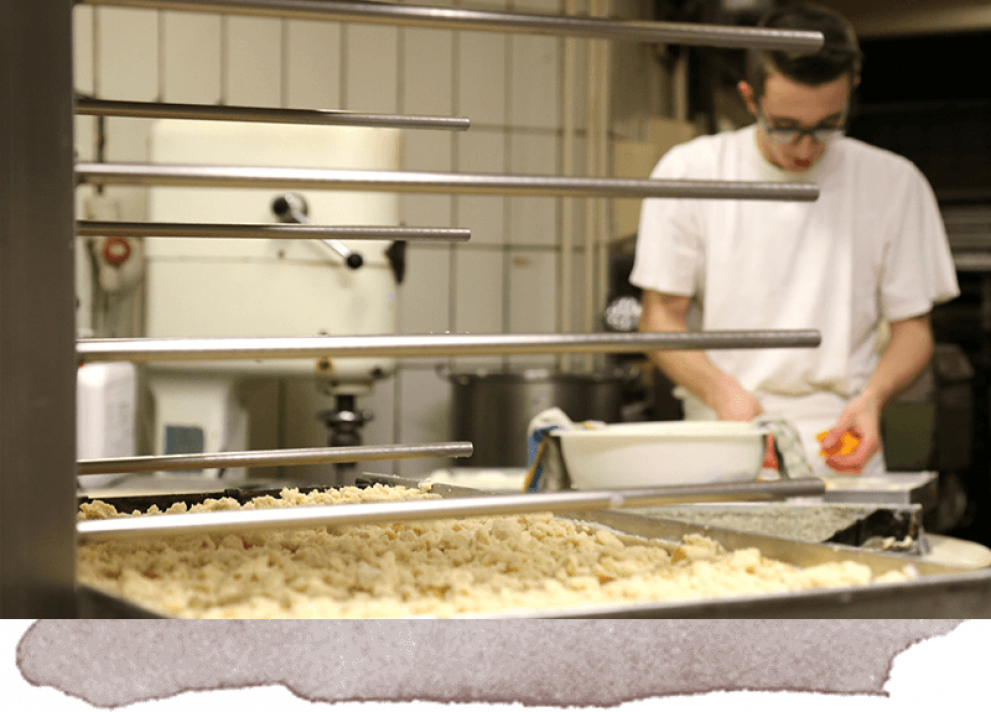 Bäckerei-Mitarbeiter beim belegen eines Streuselkuchens